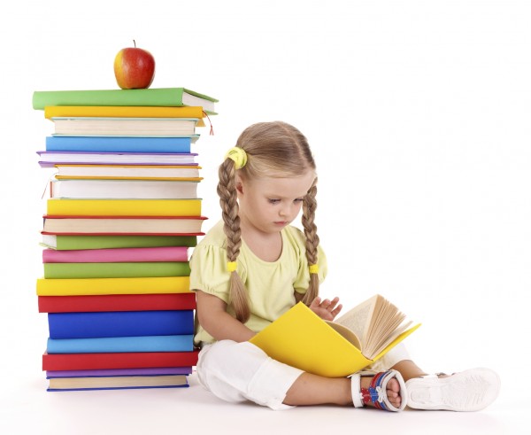 Child reading pile of books.